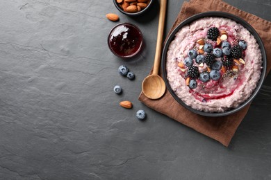 Photo of Tasty oatmeal porridge with toppings served on dark table, flat lay. Space for text