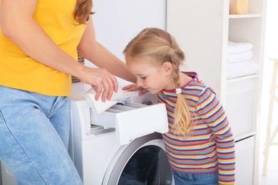 Photo of Little girl helping her mother to do laundry at home