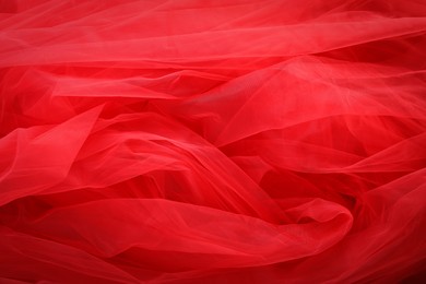 Photo of Beautiful red tulle fabric as background, closeup