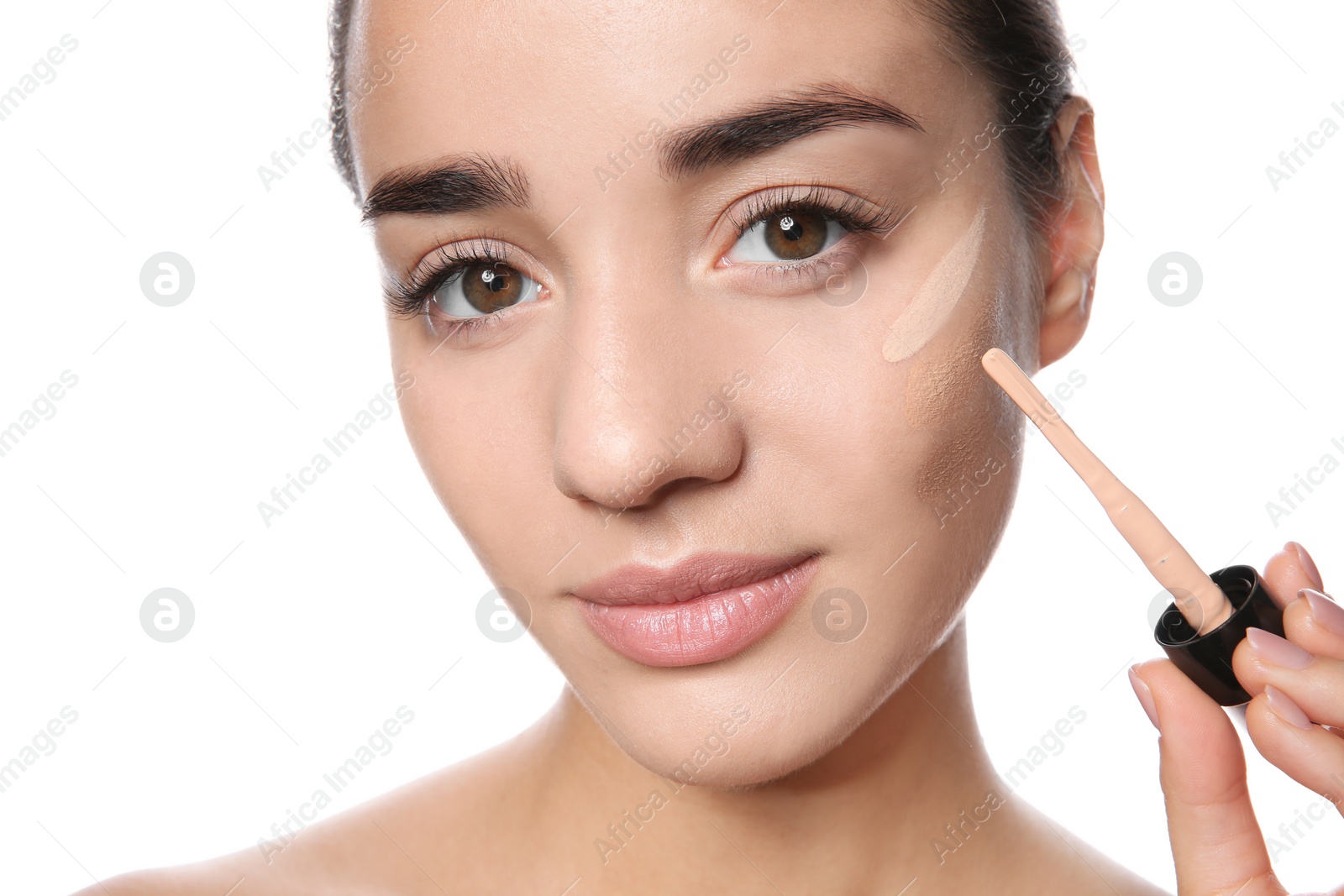 Photo of Young woman applying foundation on her face against white background