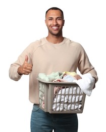 Happy man with basket full of laundry showing thumb up on white background