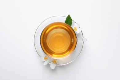 Photo of Glass cup of aromatic jasmine tea and fresh flowers on white background, top view