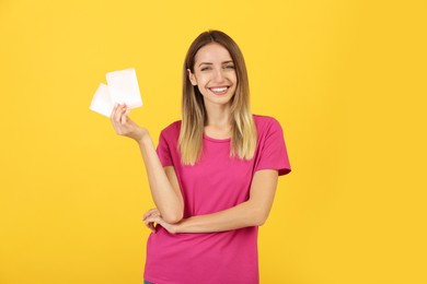 Happy young woman with disposable menstrual pads on yellow background
