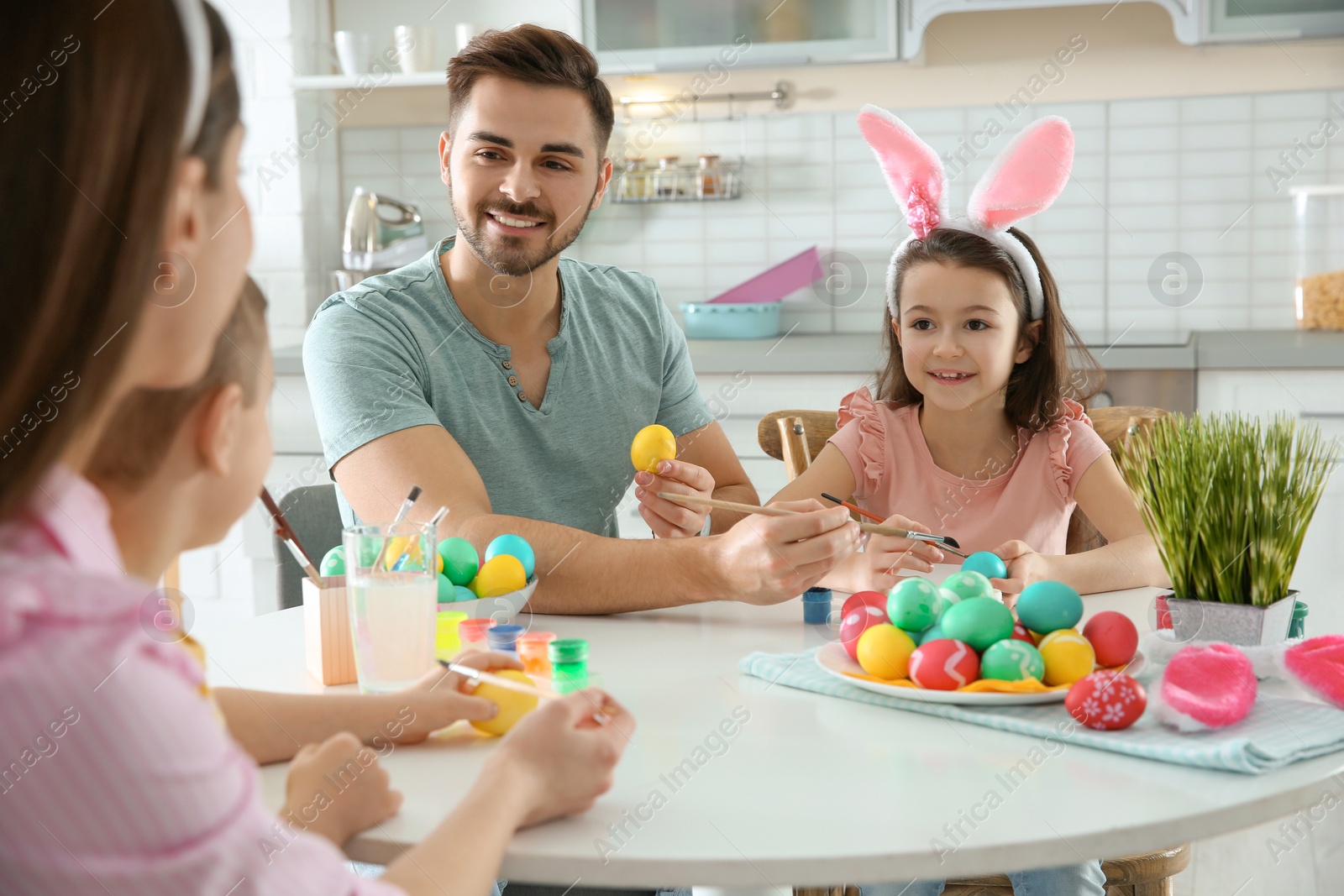 Photo of Happy family painting Easter eggs in kitchen. Festive tradition