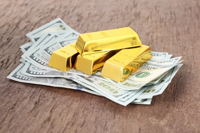 Photo of Shiny gold bars and dollar bills on table
