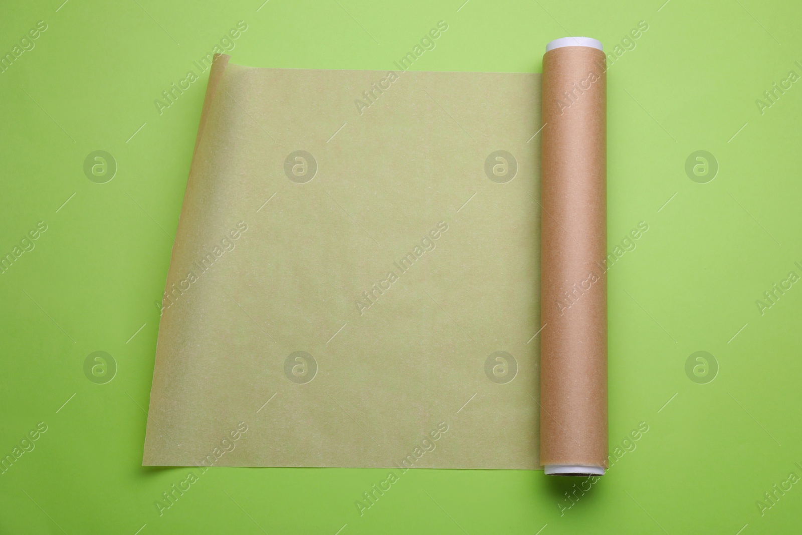 Photo of Roll of baking paper on light green background, top view