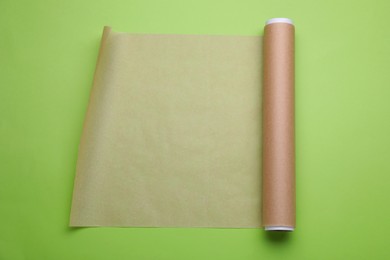 Roll of baking paper on light green background, top view