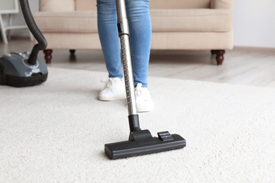 Woman cleaning carpet with vacuum in living room