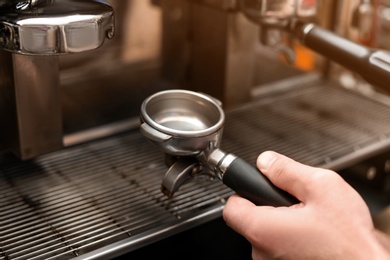 Photo of Male barista making espresso using professional coffee machine, closeup