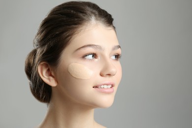Photo of Beautiful girl with foundation smear on her face against grey background