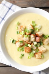 Photo of Tasty potato soup with croutons and green onion in bowl on table, top view