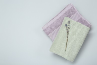 Photo of Different soft towels and lavender flowers on light grey background, top view. Space for text