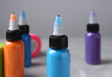 Photo of Colorful tattoo inks on light grey table, closeup