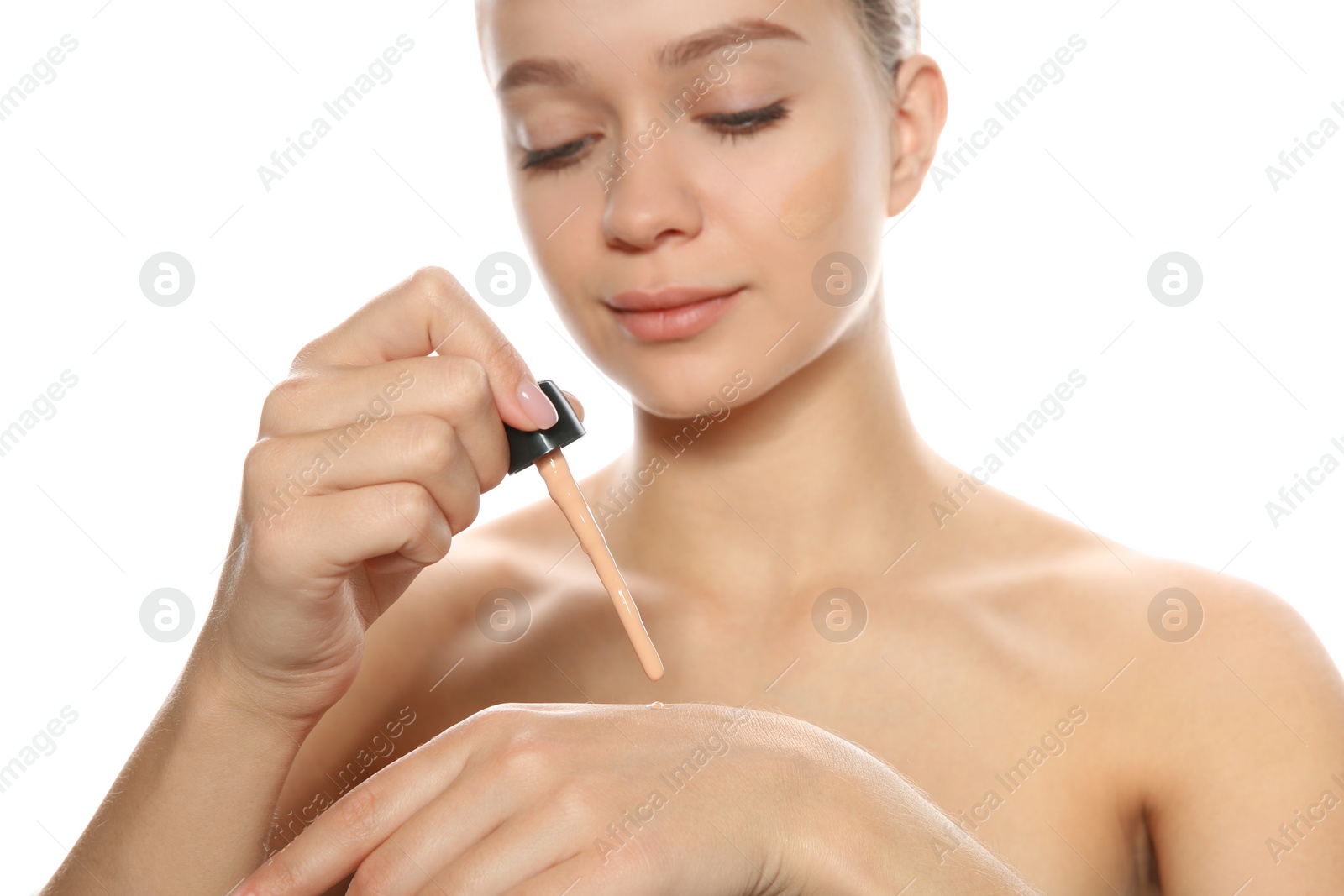 Photo of Young woman testing liquid foundation on her hand against white background