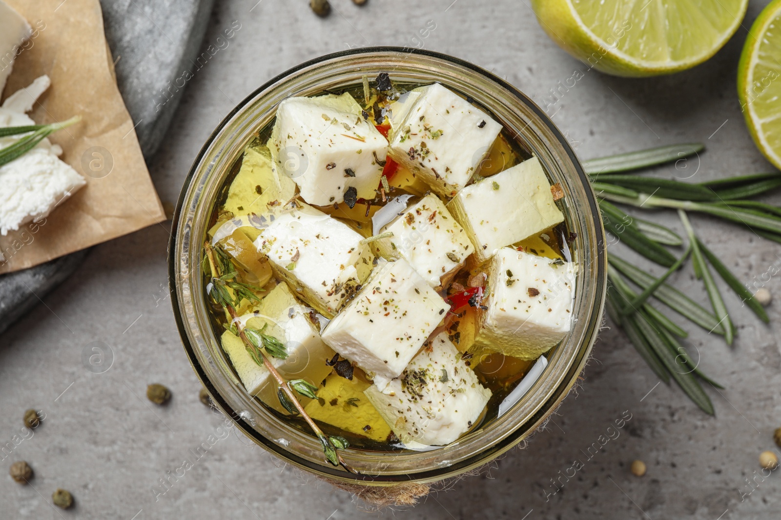 Photo of Flat lay composition with pickled feta cheese in jar on grey table