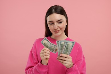 Woman with dollar banknotes on pink background