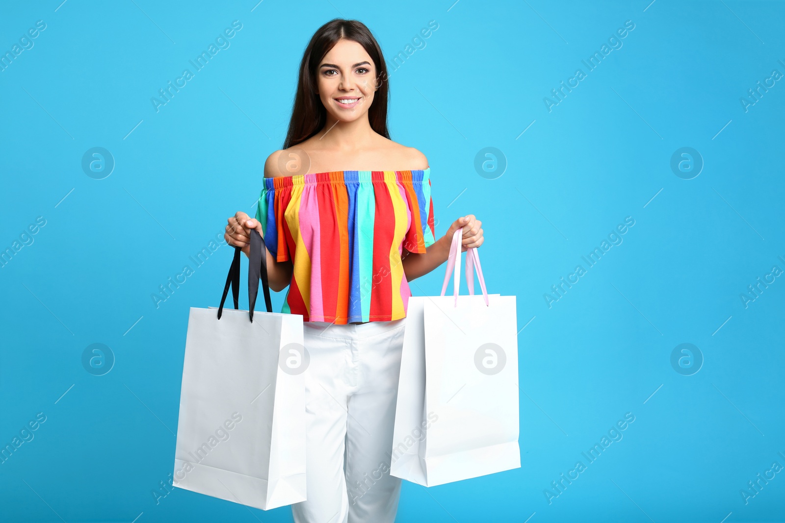 Photo of Portrait of young woman with paper bags on blue background