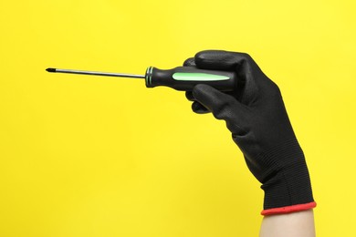 Photo of Woman holding screwdriver on yellow background, closeup