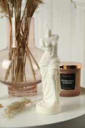 Photo of Venus De Milo candle on white table. Stylish decor