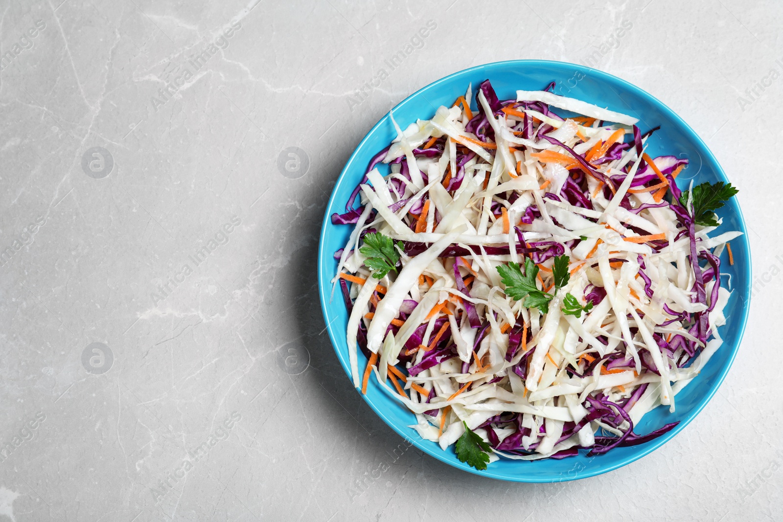 Photo of Tasty salad with cabbage on light grey marble table, top view. Space for text