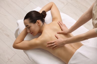 Woman receiving back massage on couch in spa salon, top view