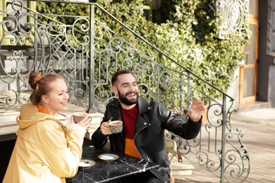 Lovely young couple enjoying tasty coffee at table outdoors