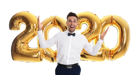 Photo of Happy young man near golden 2020 balloons on white background. New Year celebration