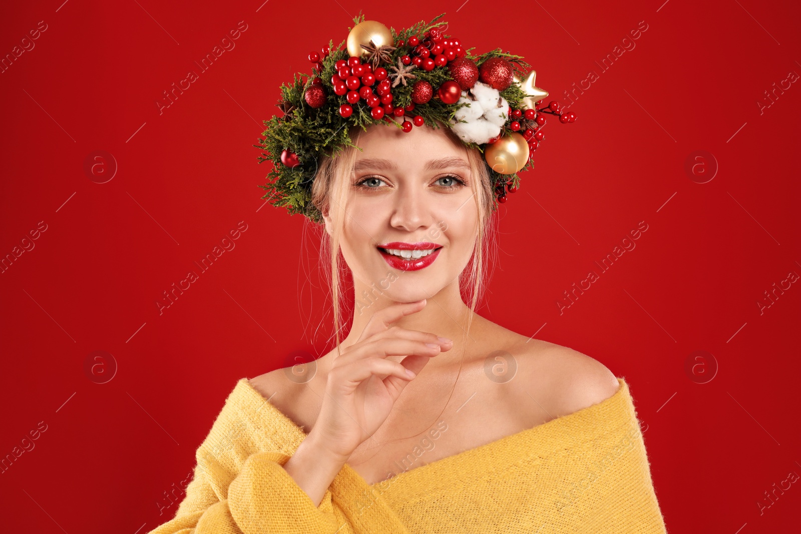 Photo of Beautiful young woman wearing Christmas wreath on red background