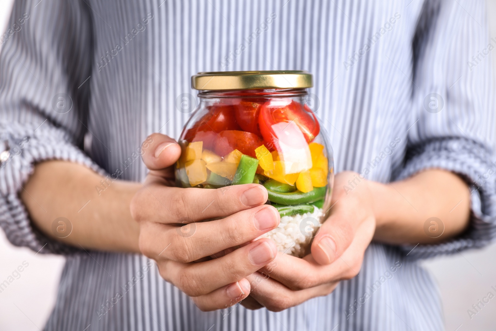 Photo of Woman holding glass jar with healthy meal, closeup