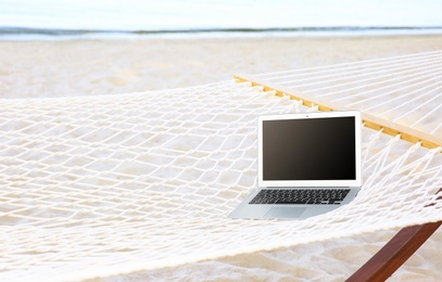 Comfortable hammock with laptop at seaside. Summer vacation