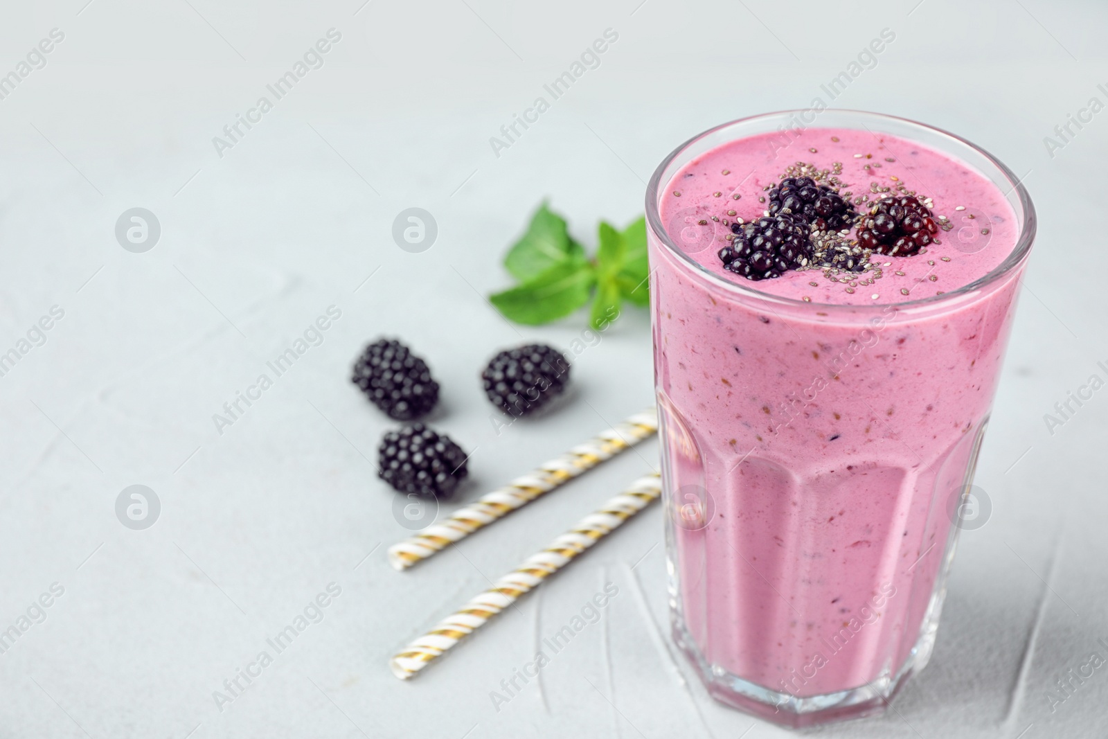 Photo of Delicious blackberry smoothie in glass on light table. Space for text