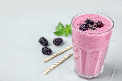 Delicious blackberry smoothie in glass on light table. Space for text