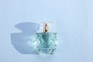 Photo of Luxury women's perfume. Sunlit glass bottle on grey background, top view