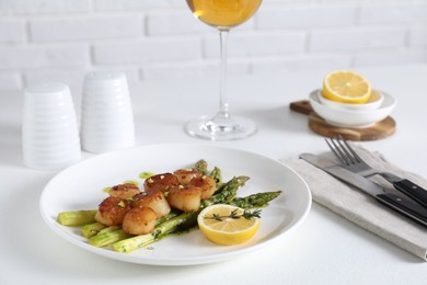 Photo of Delicious fried scallops with asparagus, lemon and thyme served on white table