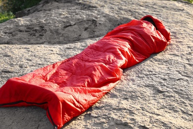 Photo of Woman resting in sleeping bag on rock outdoors