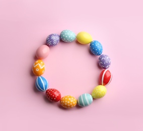 Photo of Frame made of painted Easter eggs on color background, top view. Space for text