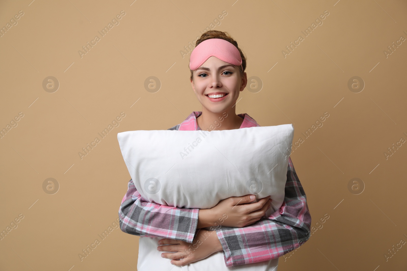 Photo of Beautiful woman with pillow on beige background. Bedtime