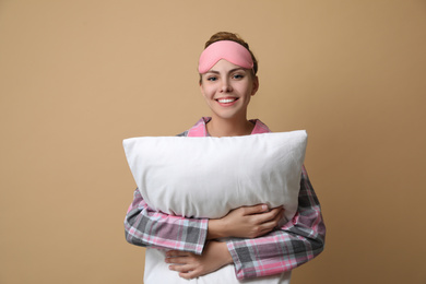 Beautiful woman with pillow on beige background. Bedtime