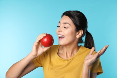 Photo of Young woman with healthy teeth and apple on color background