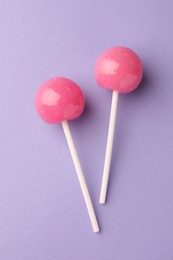 Tasty lollipops on violet background, flat lay