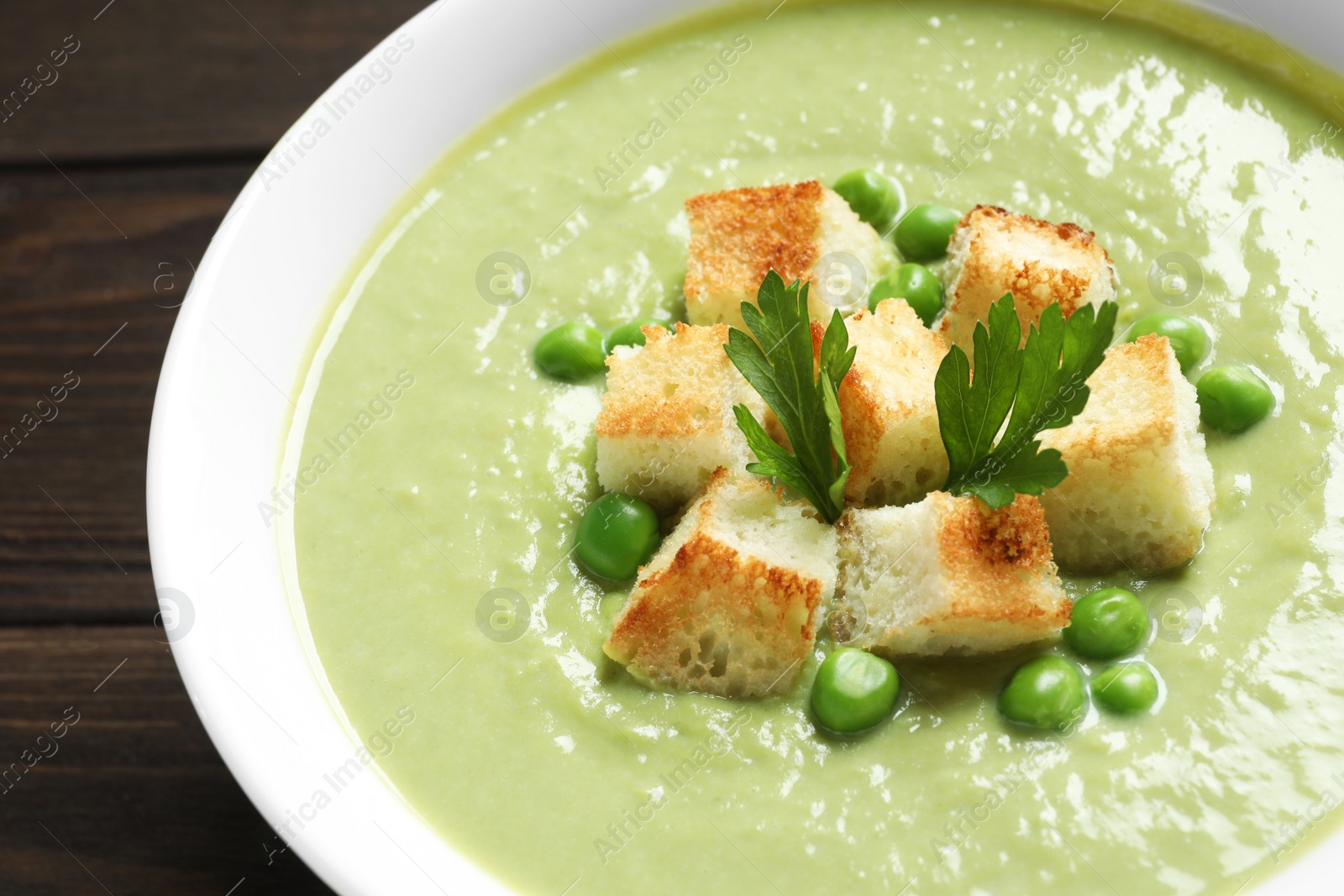 Photo of Fresh vegetable detox soup made of green peas with croutons in dish, closeup