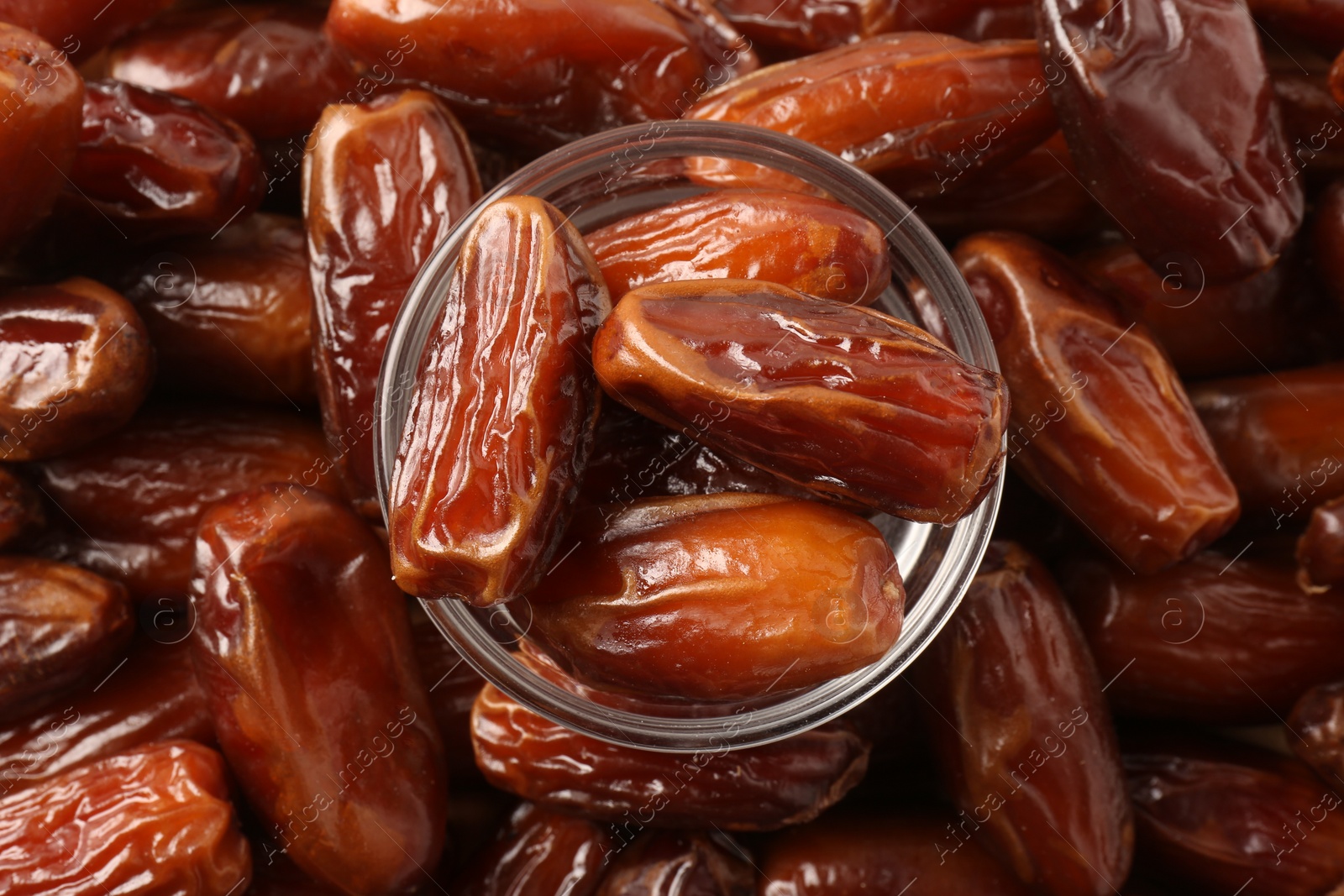 Photo of Tasty sweet dried dates and glass bowl, top view