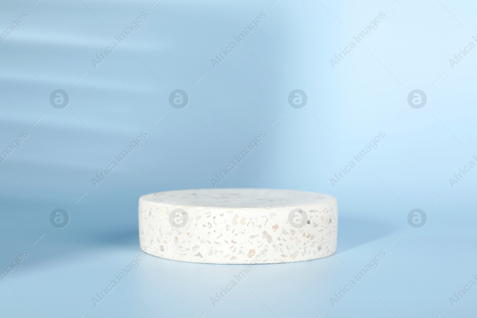Photo of Presentation of product. Round podium and shadows on light blue background. Space for text