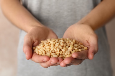 Photo of Woman holding shelled pine nuts, closeup. Organic snack