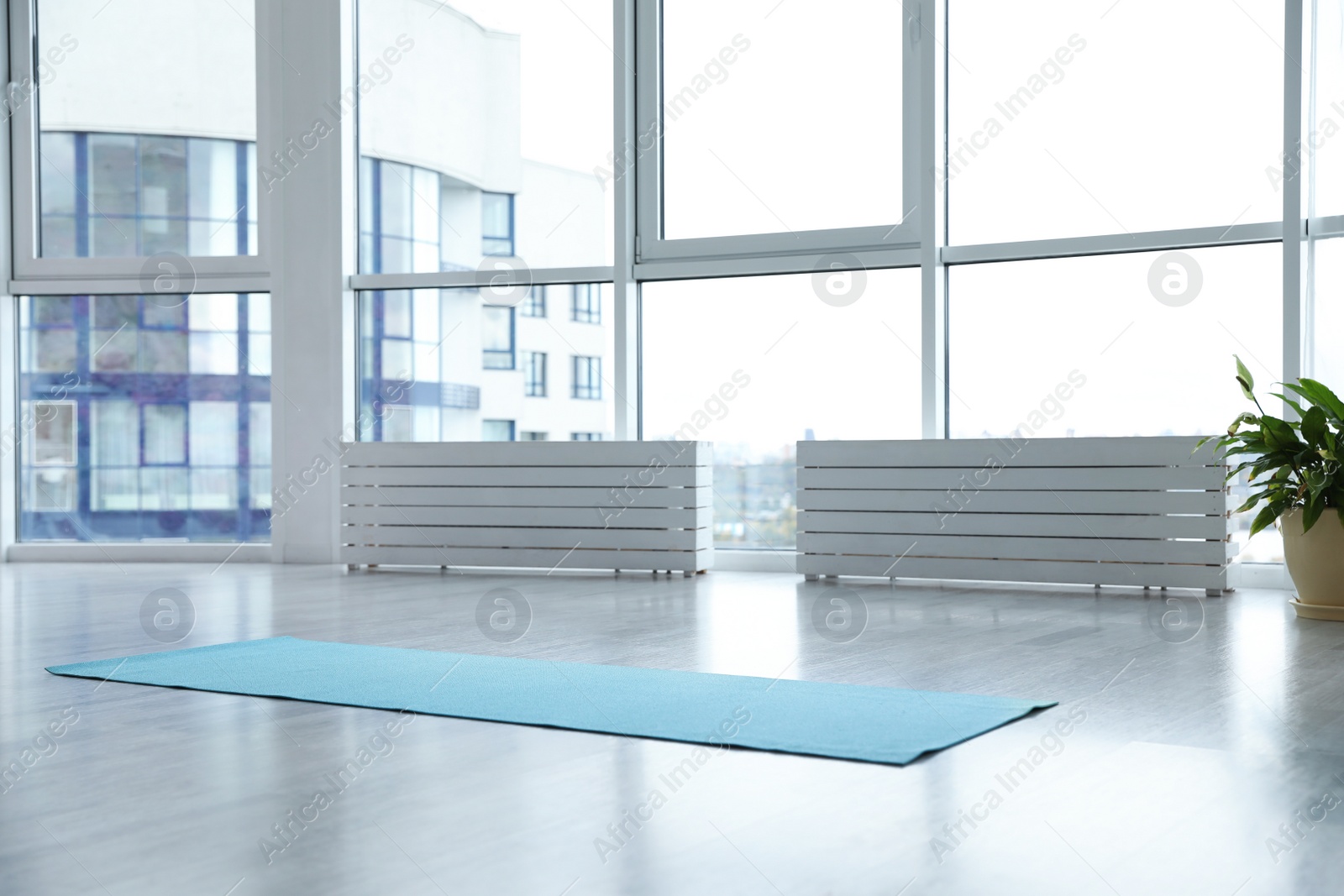 Photo of Unrolled light blue yoga mat on floor in room