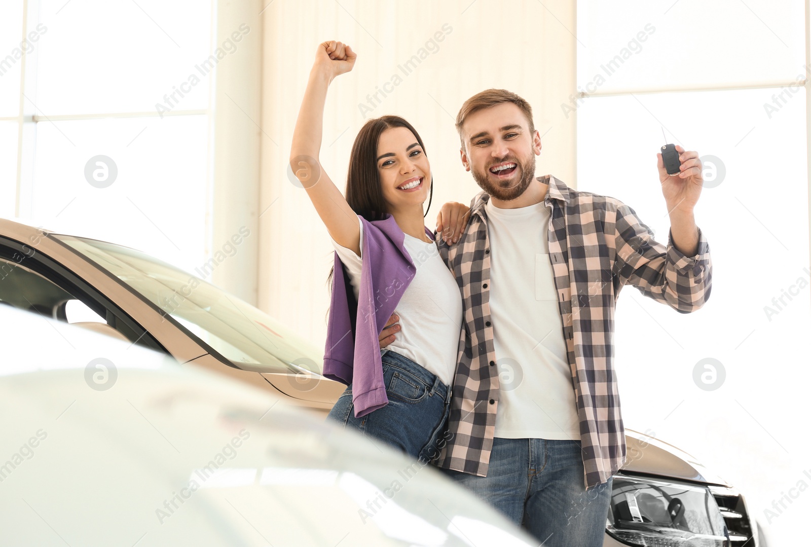 Photo of Happy couple with car key in modern auto dealership