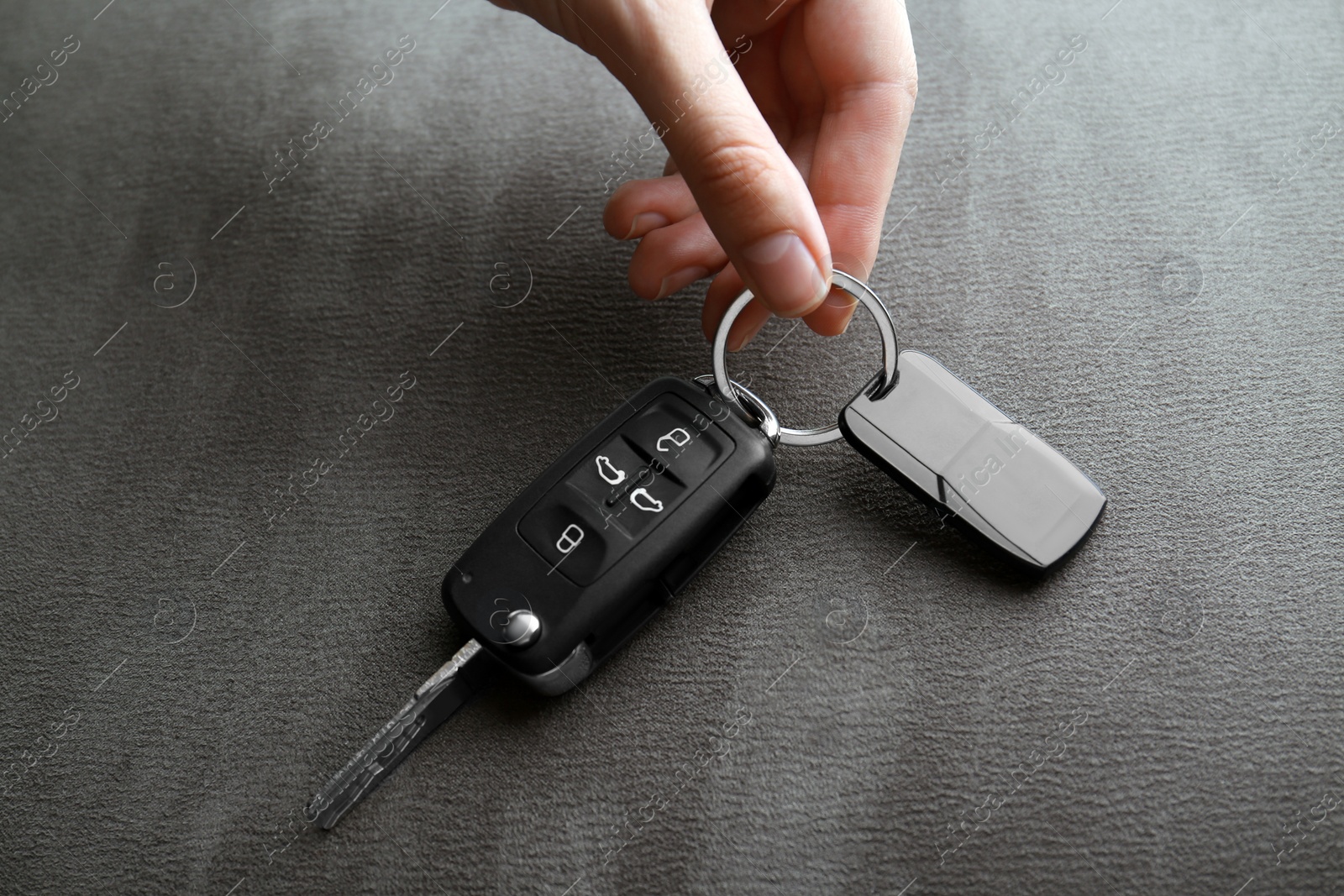 Woman holding car flip key on grey background, closeup Photo of Woman holding car flip key on grey background, closeup