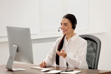 Photo of Hotline operator with headset working on computer in office