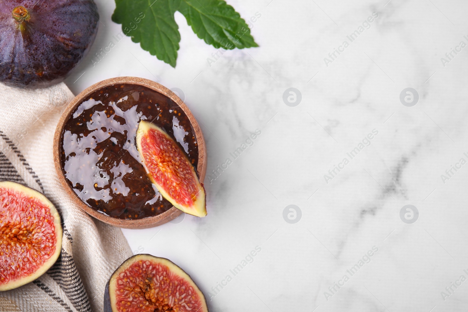 Photo of Bowl of tasty sweet fig jam and fruits on white marble table, flat lay. Space for text