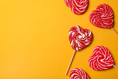 Sweet heart shaped lollipops on orange background, flat lay with space for text. Valentine's day celebration